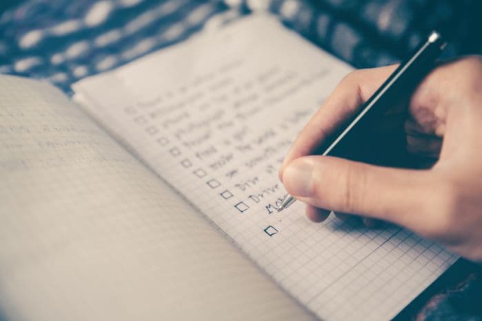 Mão escrevendo itens um caderno