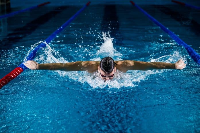 Homem nadando sozinho em piscina escura
