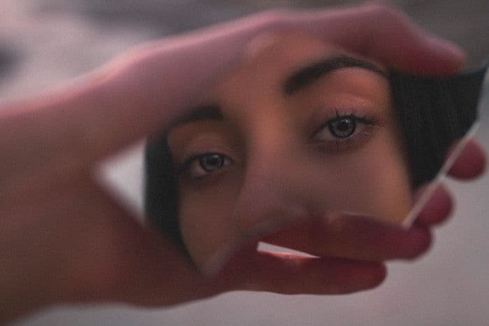 Imagem de uma mulher se olhando em espelho quebrado