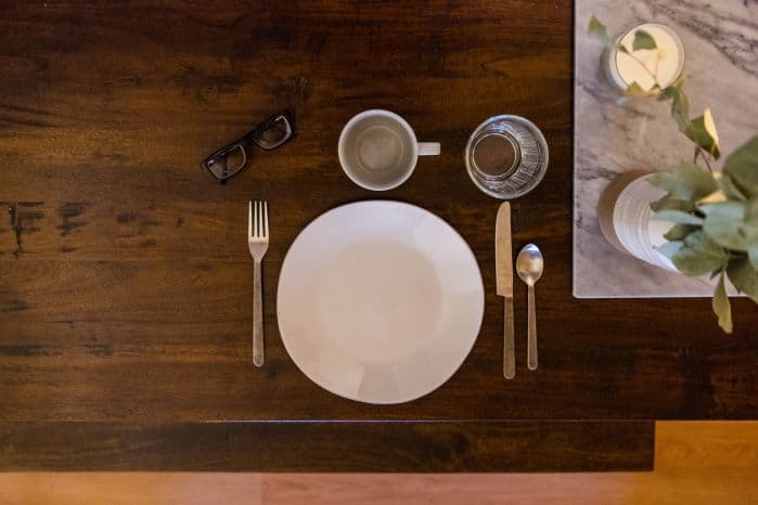Mesa montada com prato vazio e copo também.