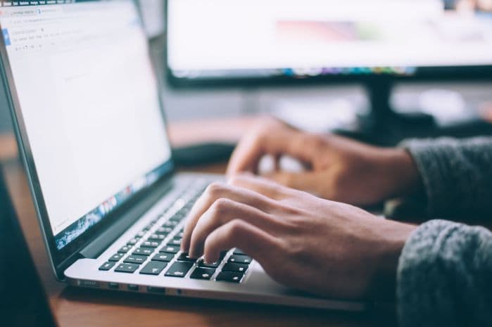 computador aberto com mãos digitando