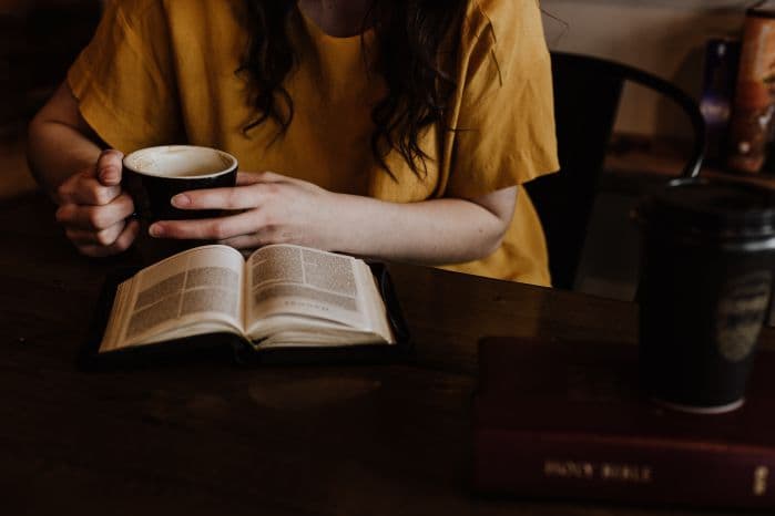 mulher lendo livro e tomando café