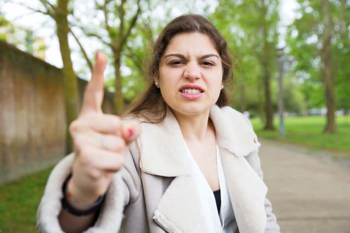 Mulher com rosto bravo e movimento do dedo como se brigasse com leitor