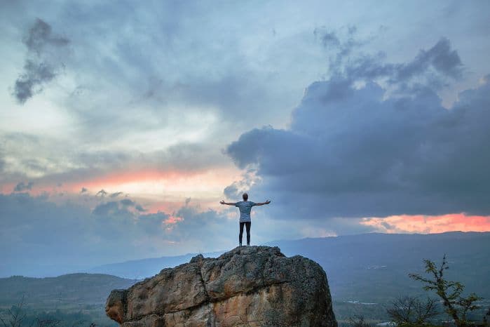 homem em meio de paisagem de braços abertos