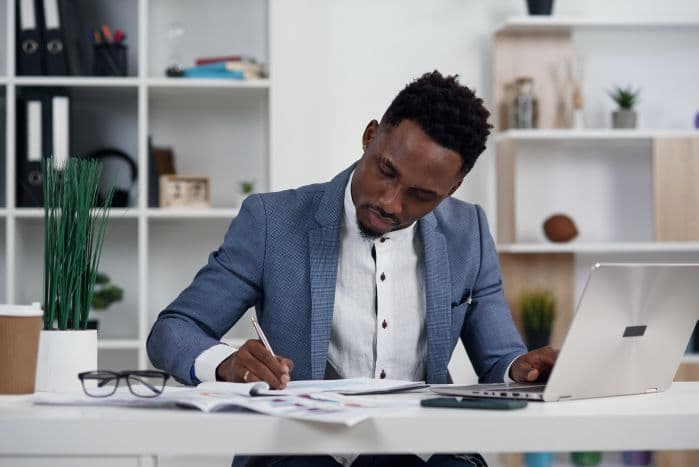 homem sentado em escritório escrevendo