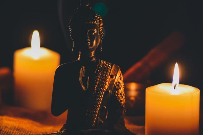 imagem da estátua do buda no meio de algumas velas